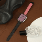 Flat lay of the pink and black Two-Tone Magnetic Apple Watch Band alongside luxury perfume and minimalist decor.