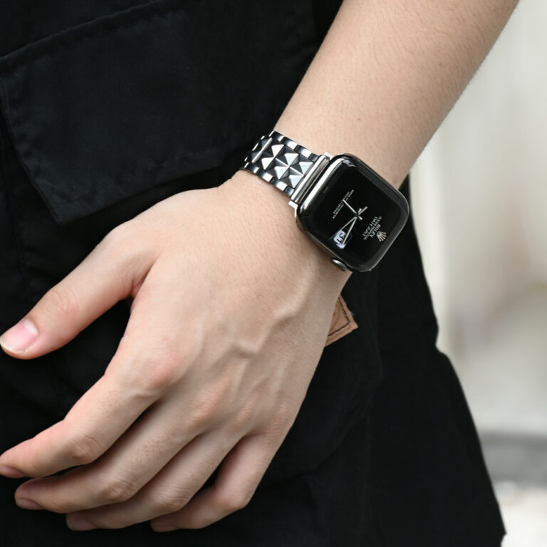 Person wearing a stainless steel pyramid Apple Watch band, luxury metal strap